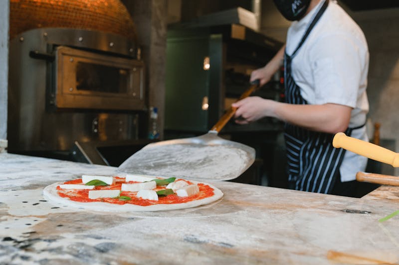 Pizza being prepared with fresh ingredients in Mod Pizza kitchen